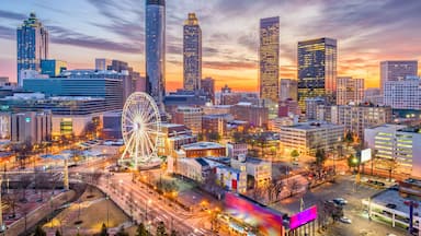 A cityscape at dusk with a prominent Ferris wheel, skyscrapers, and a sunset sky.
