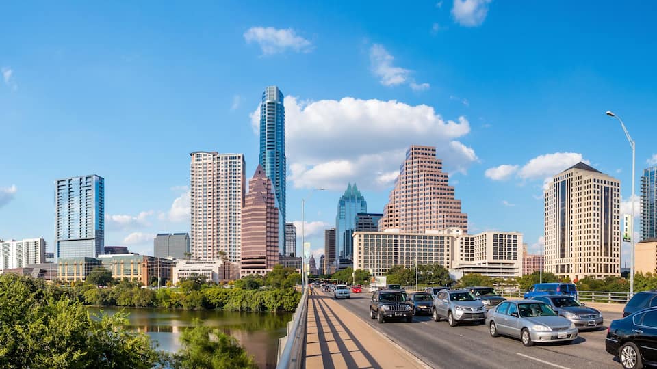 A city skyline with modern skyscrapers, a river, and a busy highway.