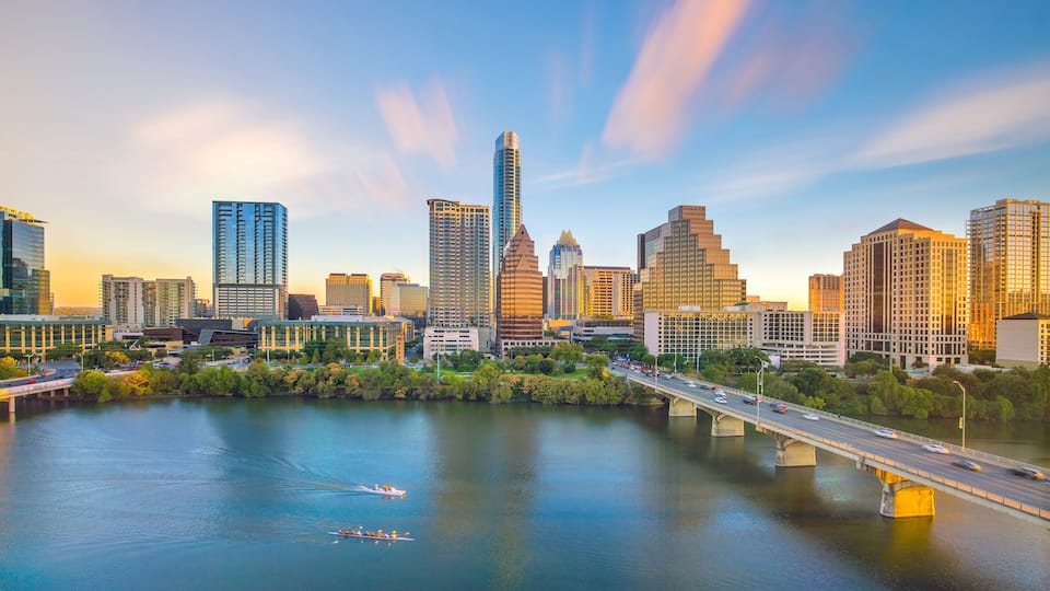 A city skyline with modern high-rise buildings, a river, and a bridge.