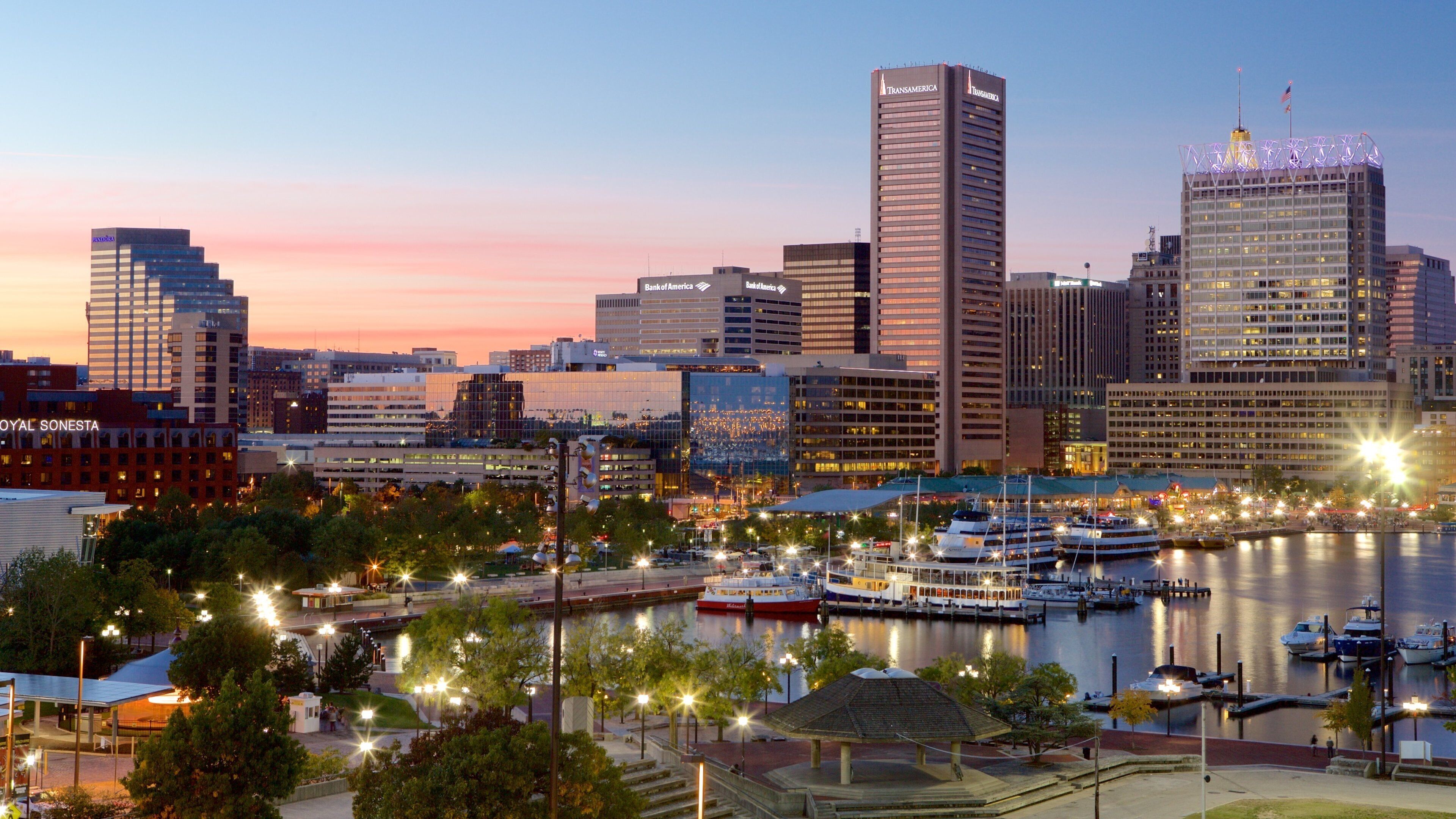 A city skyline with prominent buildings like Transamerica and Bank of America, a marina with boats, and a sunset sky.