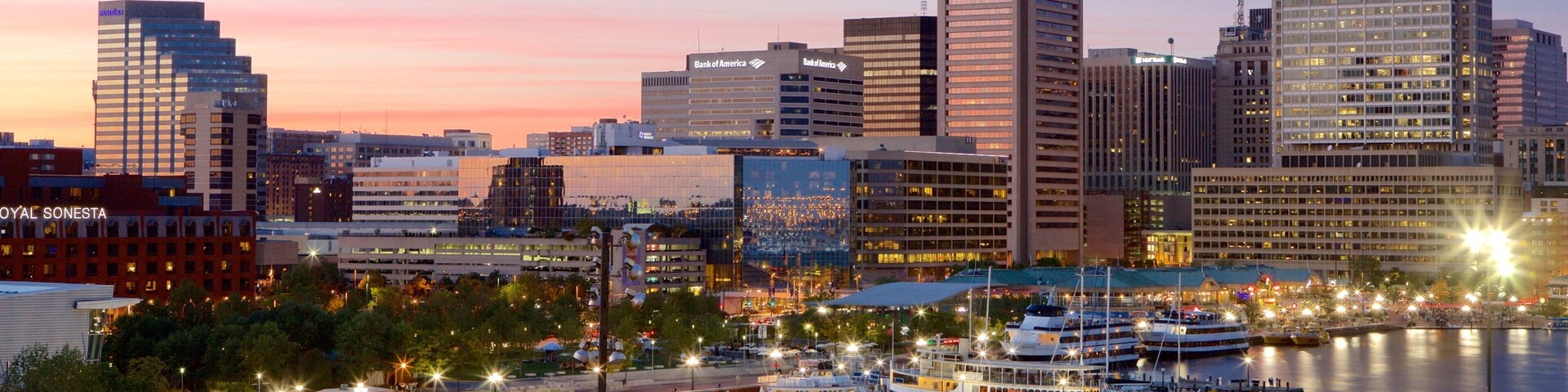 A city skyline with prominent buildings like Transamerica and Bank of America, a marina with boats, and a sunset sky.