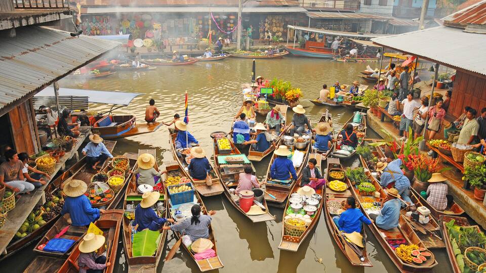 A bustling floating market with numerous wooden boats filled with various fruits and vegetables.