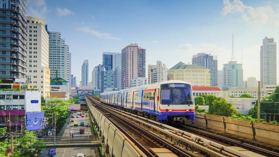 A train on elevated tracks in a city with tall buildings.
