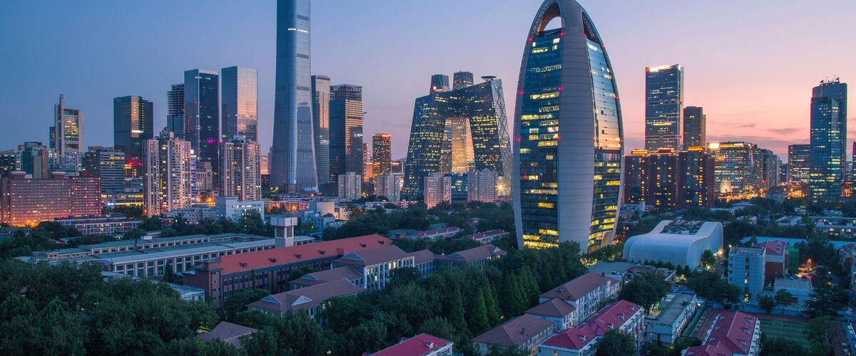 A city skyline with modern skyscrapers, including a distinctive curved building and a tall, cylindrical tower.