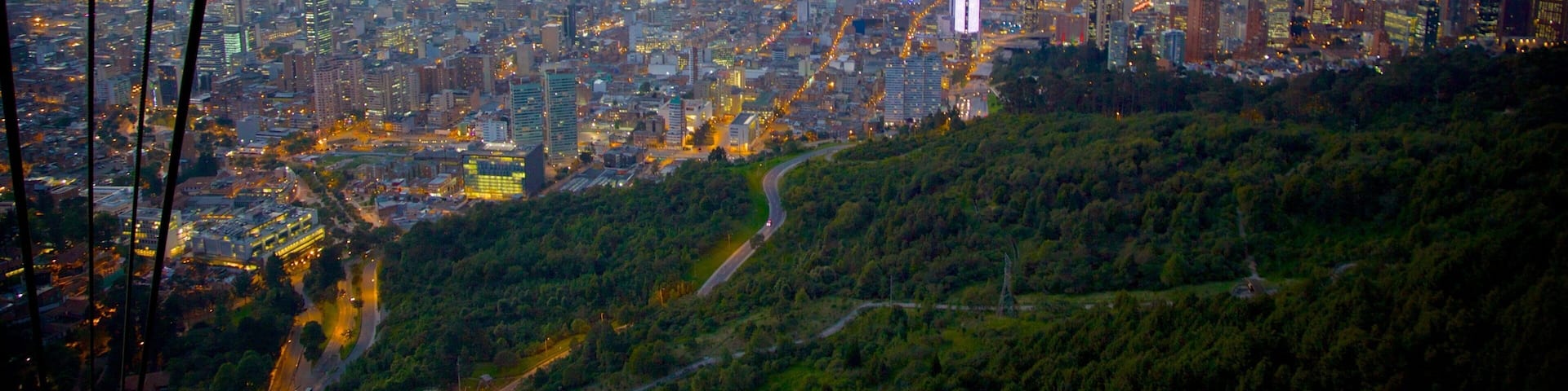 A cityscape with dense urban development, a prominent skyscraper, and surrounding green hills.