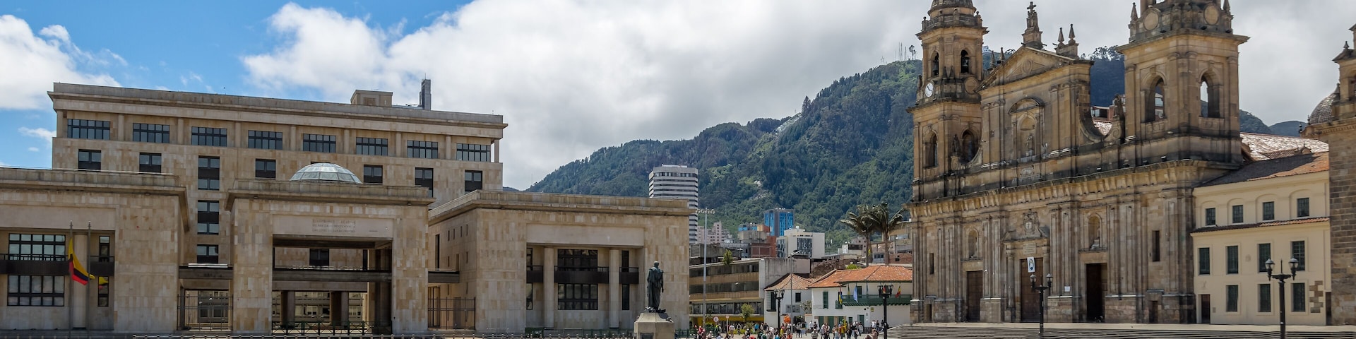Ein Platz mit einem weitläufigen offenen Bereich, einer Statue und historischen Gebäuden, darunter eine markante Kirche mit zwei Türmen.