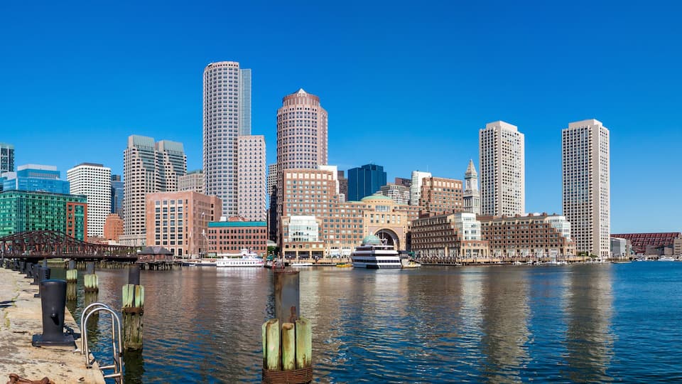 A city skyline with tall buildings along a waterfront.