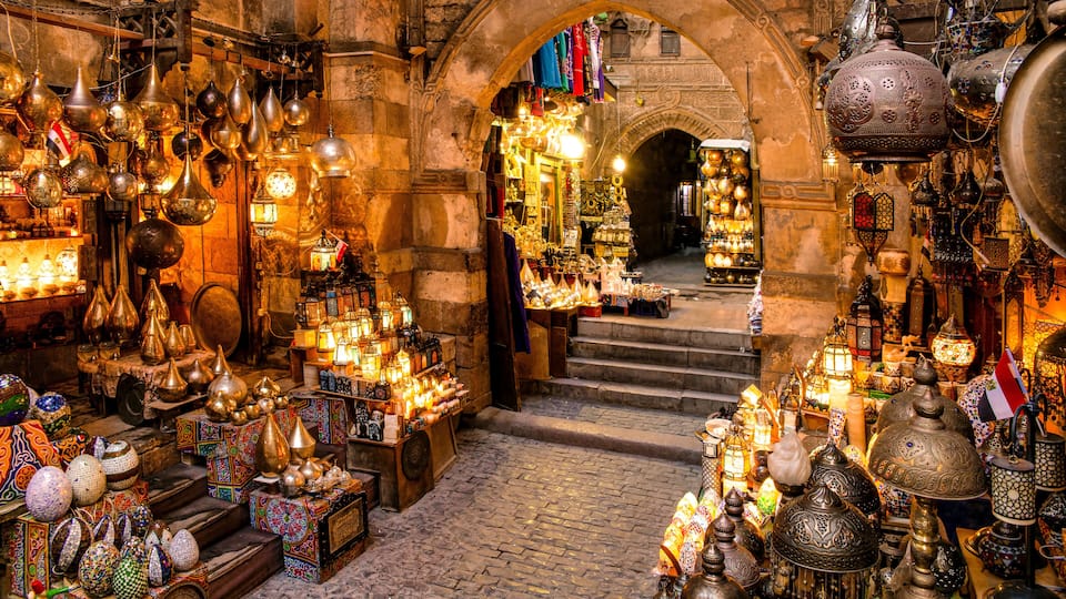 A market with various items like lanterns, pottery, and textiles displayed in an archway.
