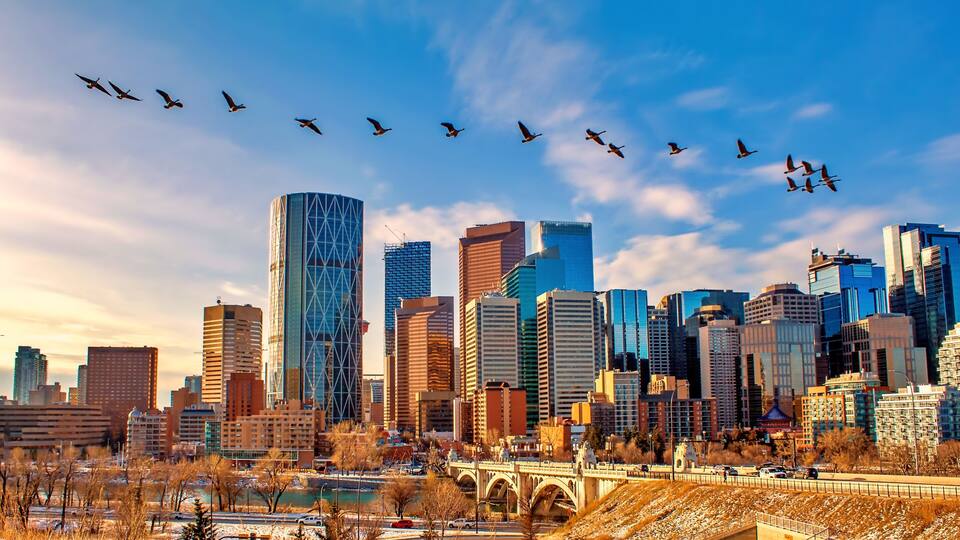 A city skyline with modern buildings and a river in the foreground.
