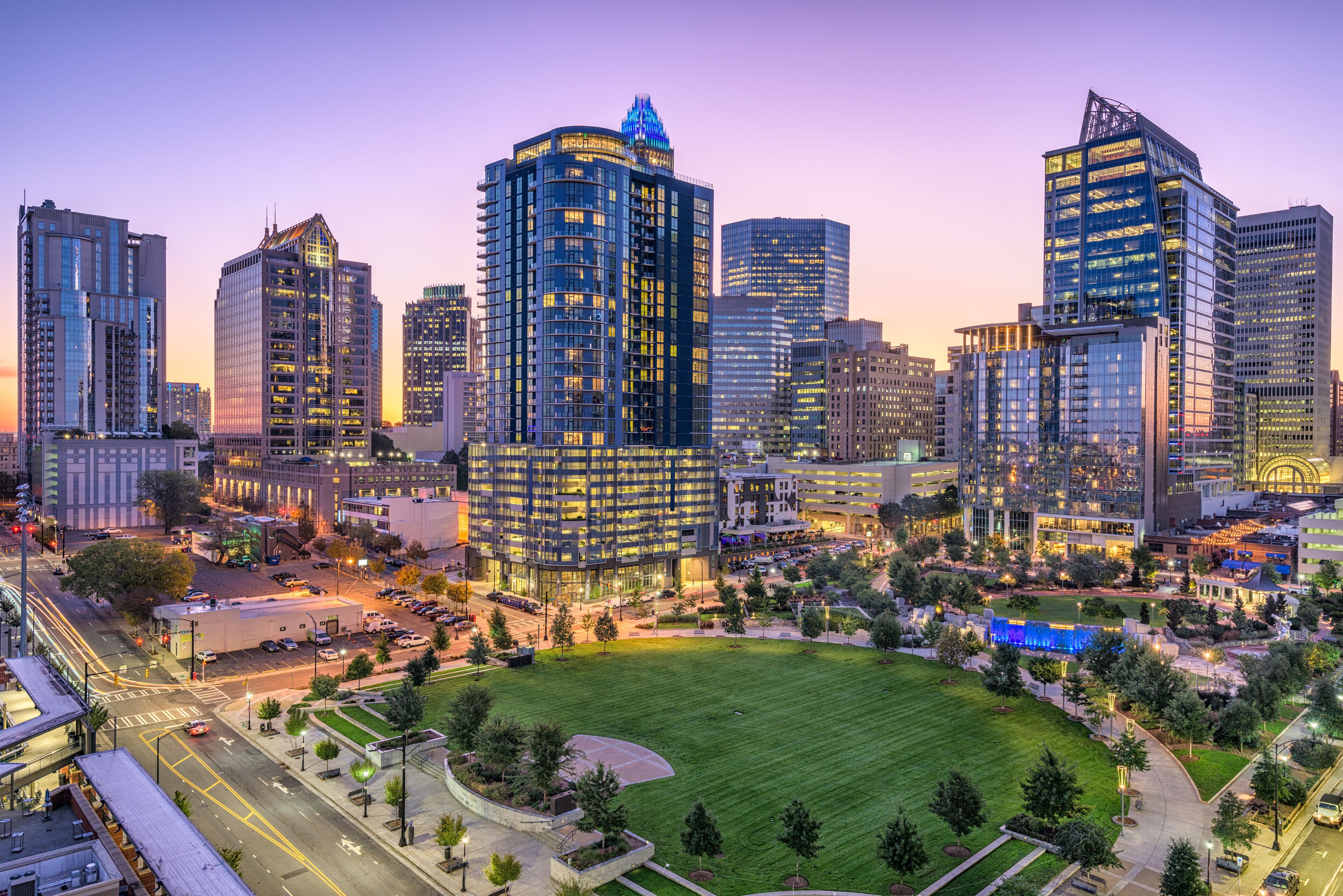 A cityscape with modern high-rise buildings, a central green park, and a well-lit urban area.