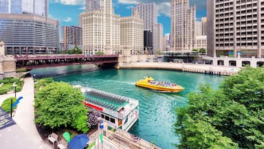 Une rivière sur laquelle flotte un bateau jaune, entourée de grands immeubles et d’un pont.