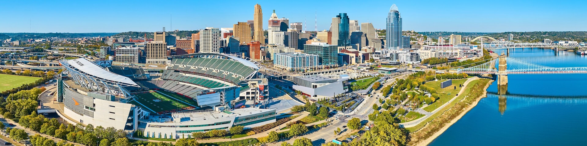 A city skyline with a prominent stadium, a river, and a bridge.