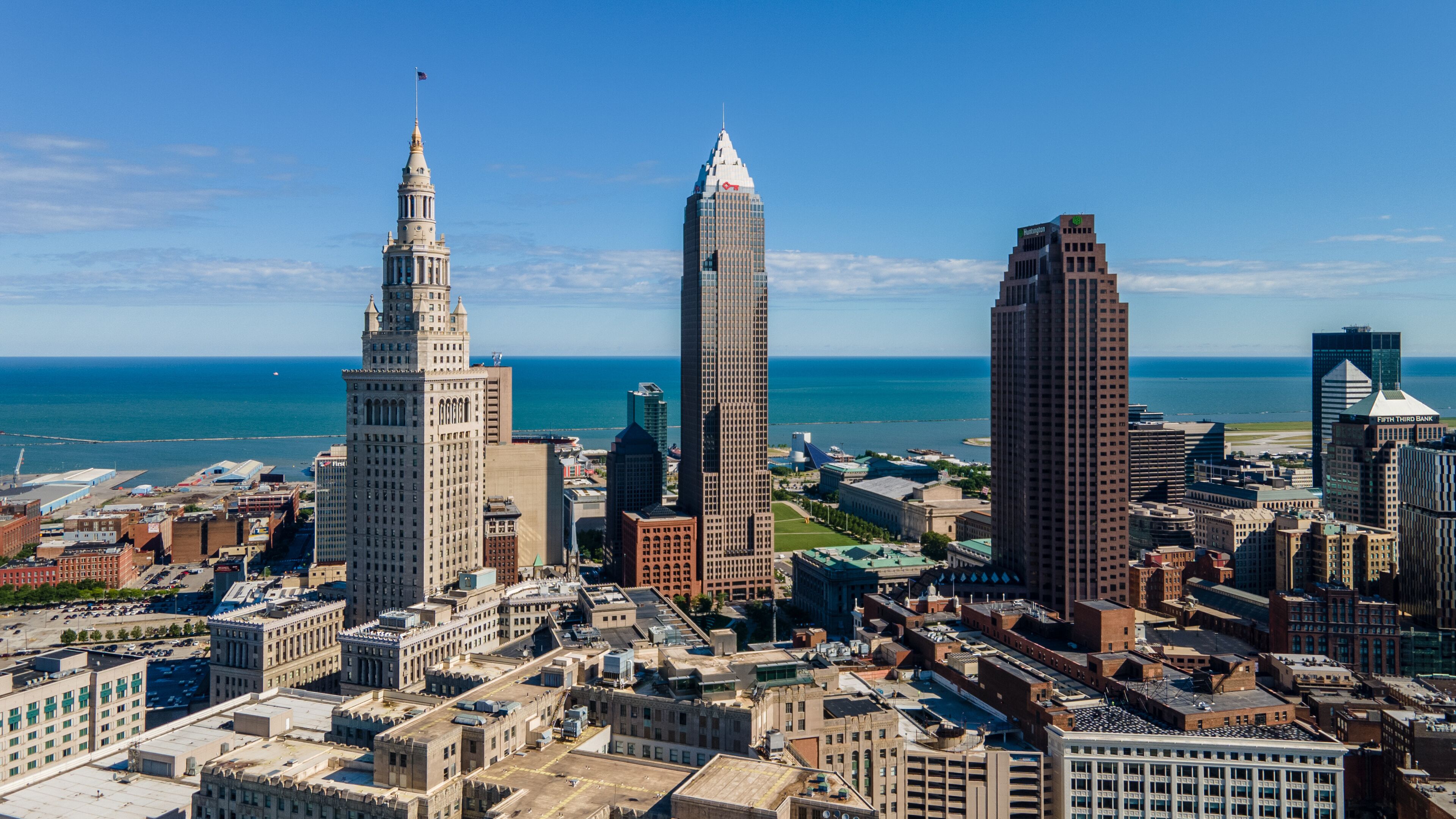 A city skyline with prominent buildings including a historic tower, a modern skyscraper, and a unique rectangular building.