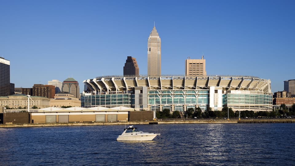 A waterfront cityscape with a prominent stadium and various modern buildings.
