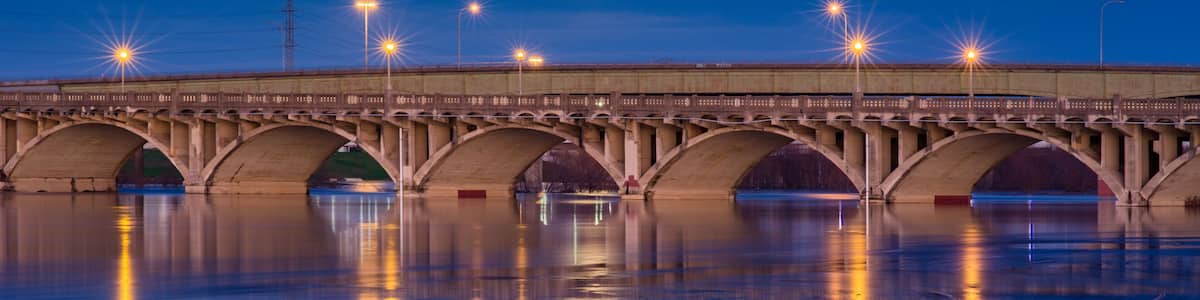 A bridge at night with lights reflecting on the water.