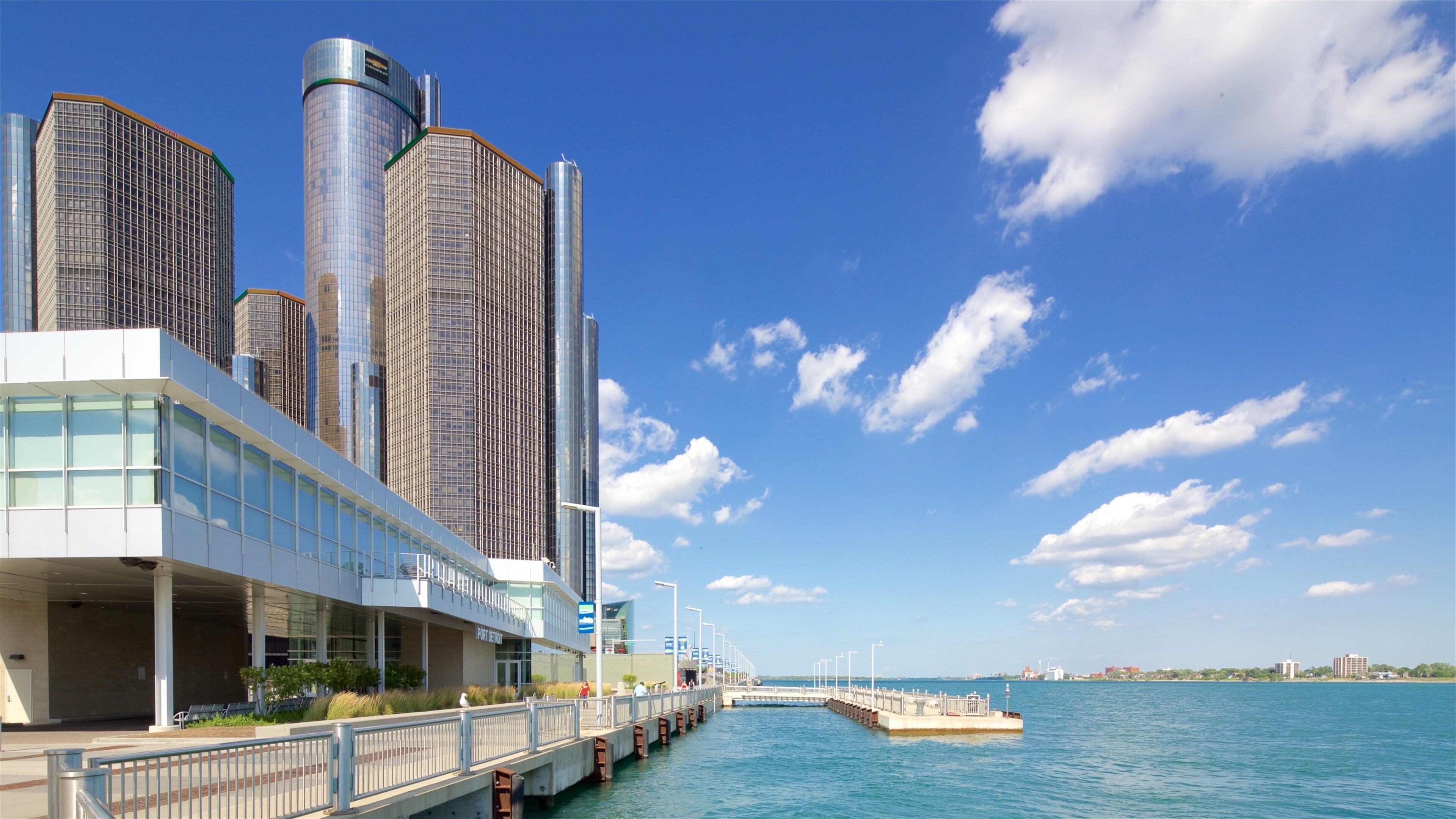 A waterfront with modern buildings, a bridge, and a clear blue sky.
