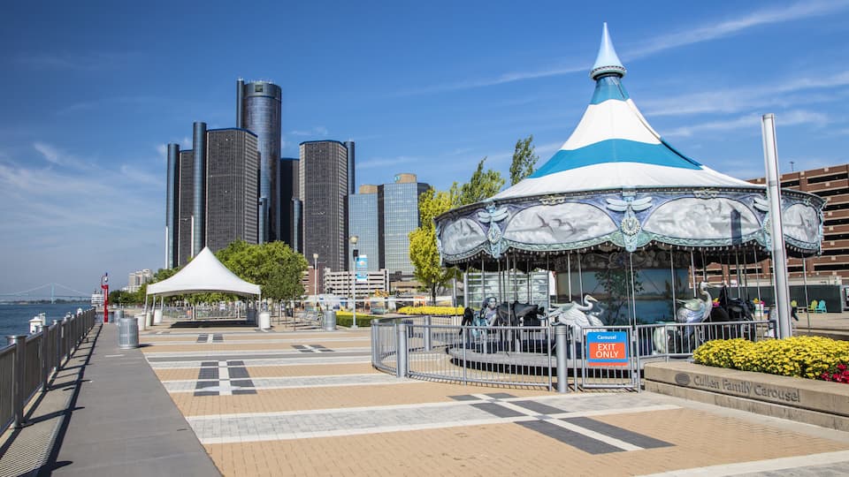 A carousel, a white tent, and a city skyline with tall buildings.