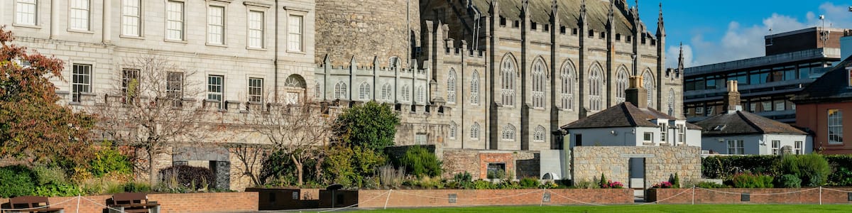 A historic castle with a round tower and a large building with arched windows.