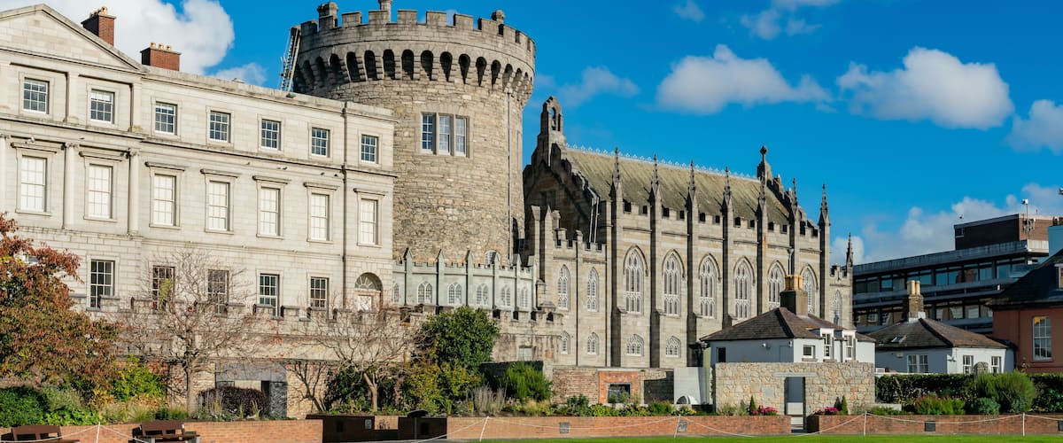 A historic castle with a round tower and a large building with arched windows.