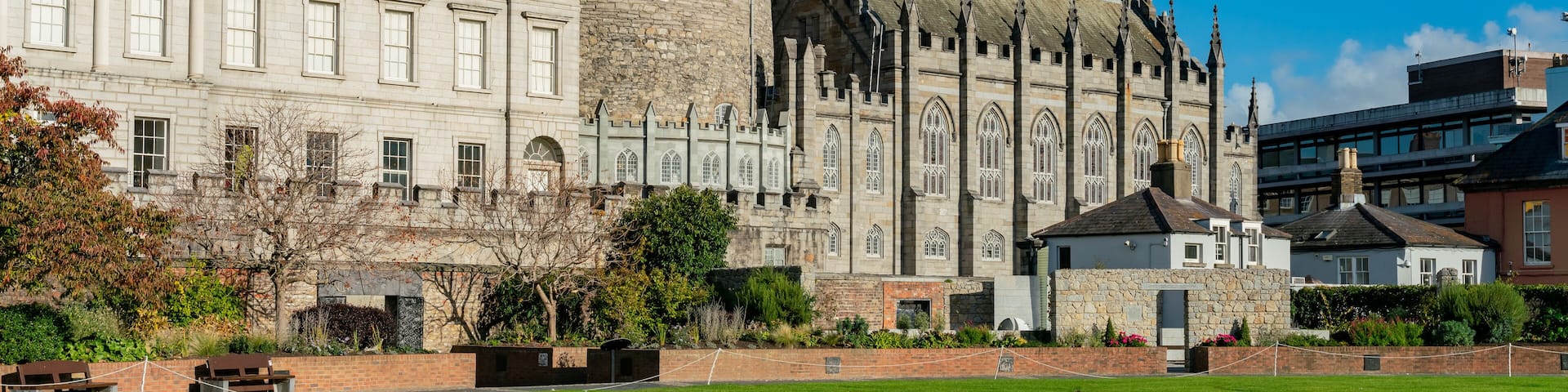 A historic castle with a round tower and a large building with arched windows.