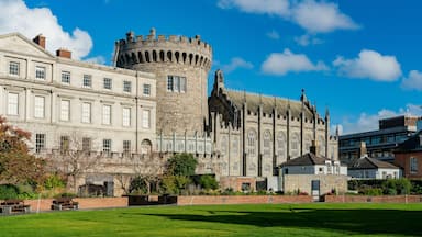 A historic castle with a round tower and a large building with arched windows.