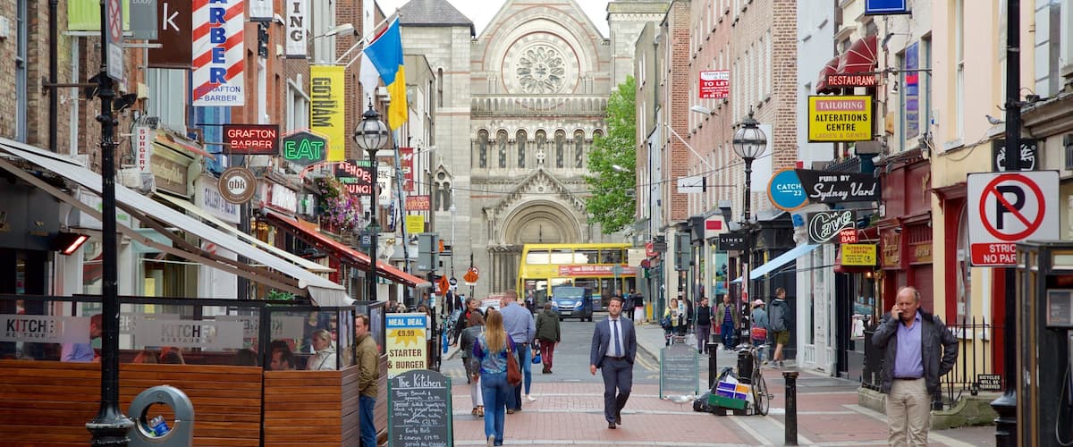 A busy street with shops, a double-decker bus, and a historic building with a clock tower.