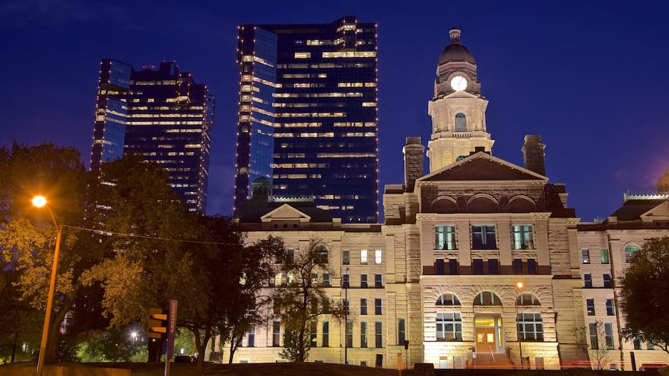 A historic building with a clock tower, surrounded by modern skyscrapers.