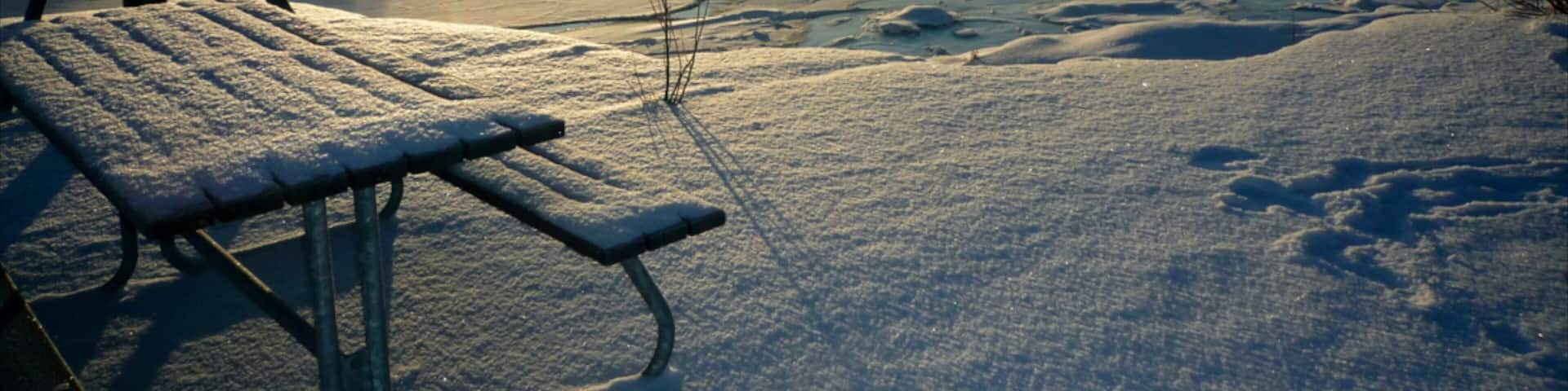 Helsinki winter landscape with frozen lake and sunlight casting shadows near Uusimaa, Finland