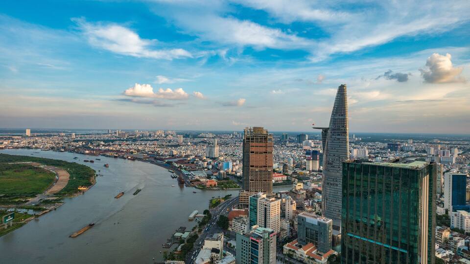A cityscape with a river, modern skyscrapers, and a distinctive tall building with a pointed top.