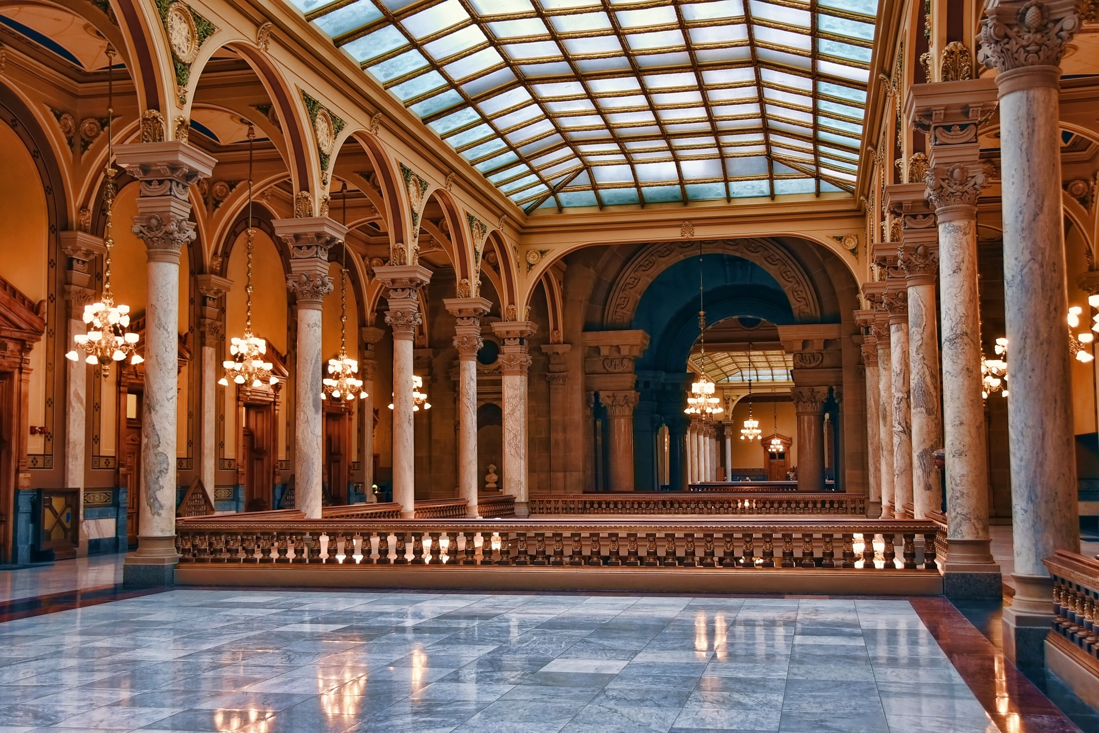 An ornate hall with high ceilings, marble columns, and chandeliers.