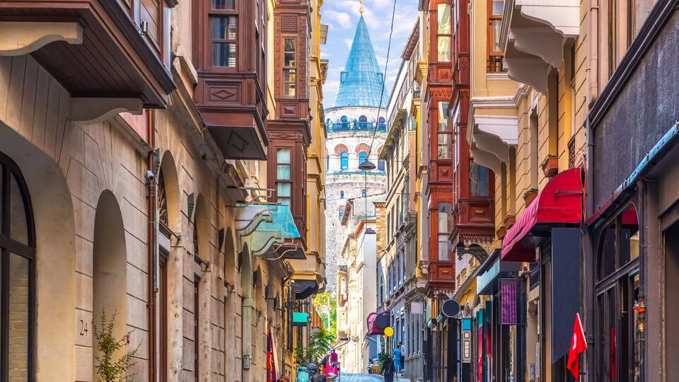 A cobblestone street lined with historic buildings, a prominent church spire, and a red flag.