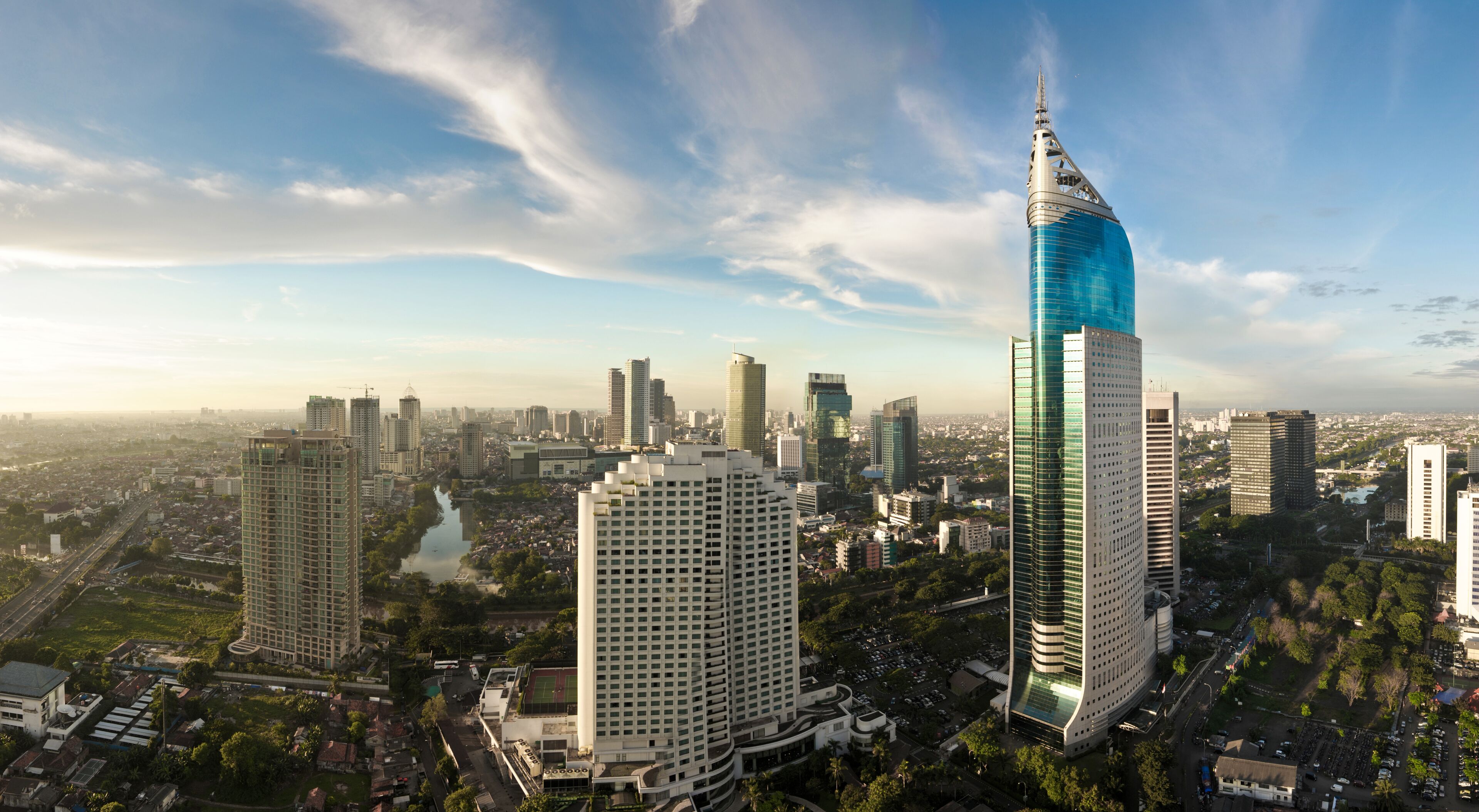 A cityscape with a prominent skyscraper with a unique design and a river running through the city.