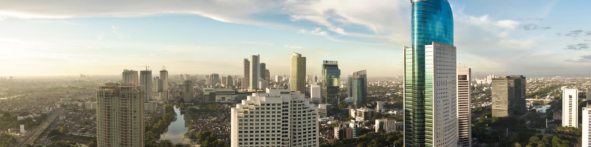 A cityscape with a prominent skyscraper with a unique design and a river running through the city.