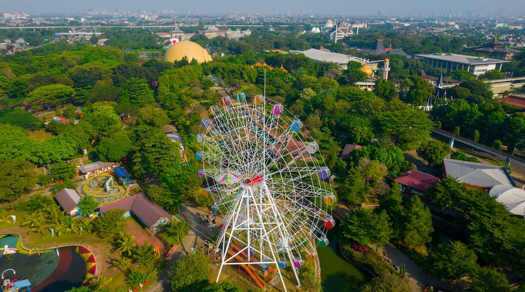 A large Ferris wheel surrounded by lush greenery and various buildings.