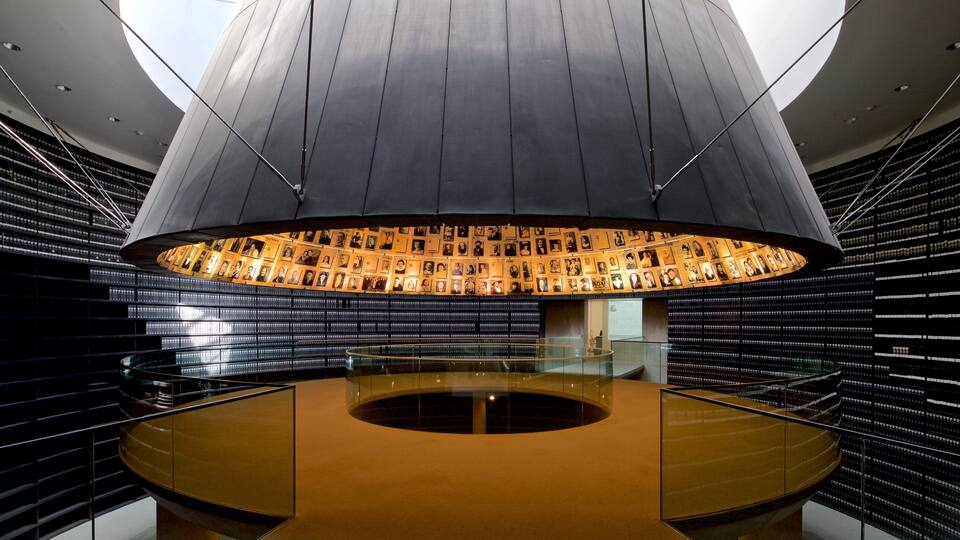 A circular room with a central light fixture and walls lined with framed photographs.