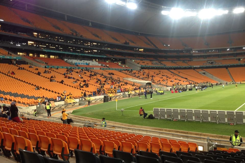 An empty stadium with orange seats and a football field.