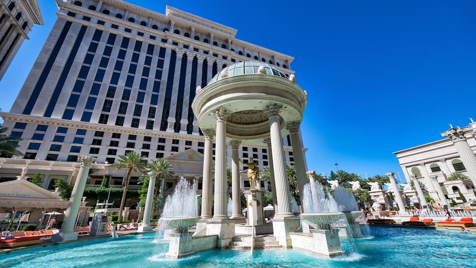A large hotel with a central fountain and palm trees.