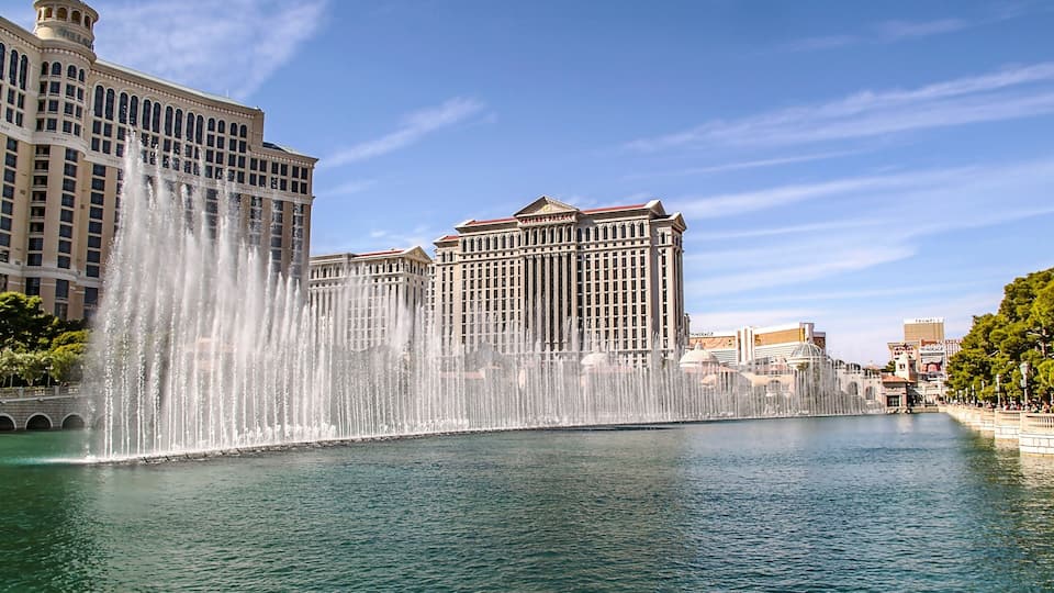 A large fountain, a casino, and a clear blue sky.