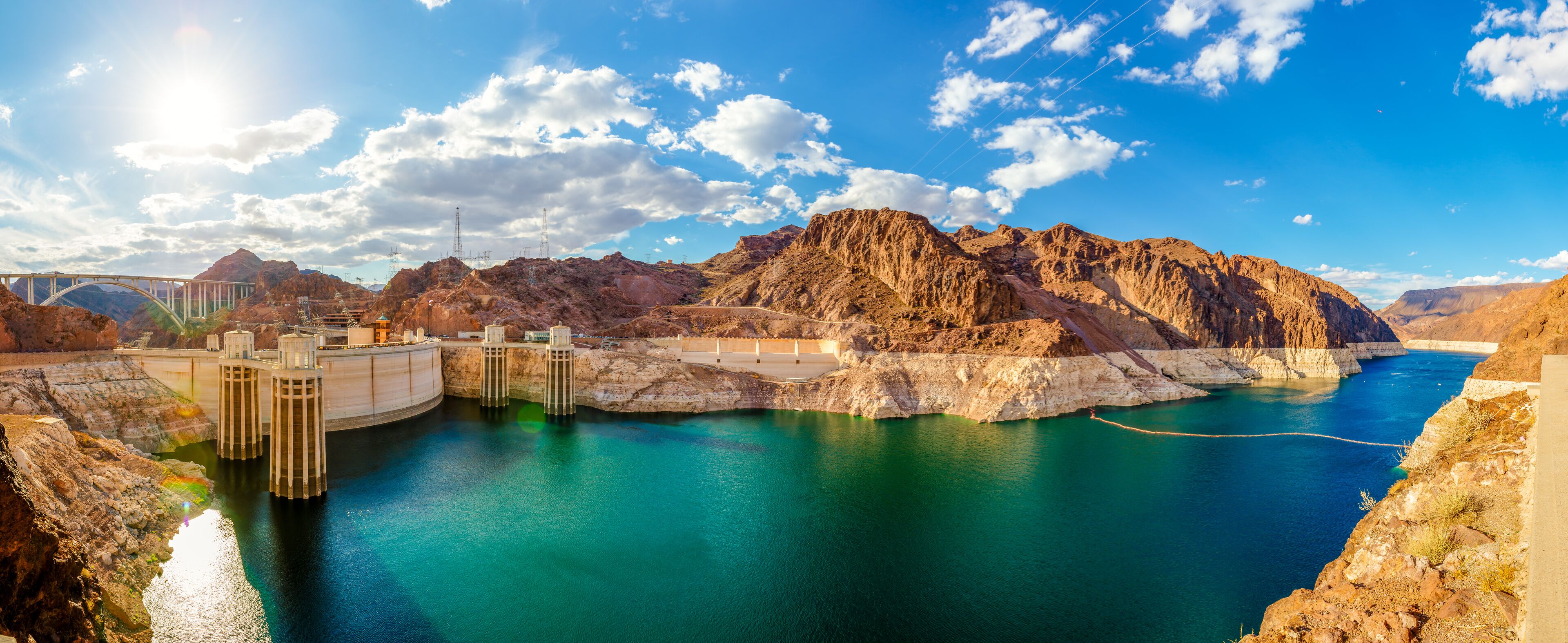 A dam with a reservoir, a bridge, and a mountainous landscape.
