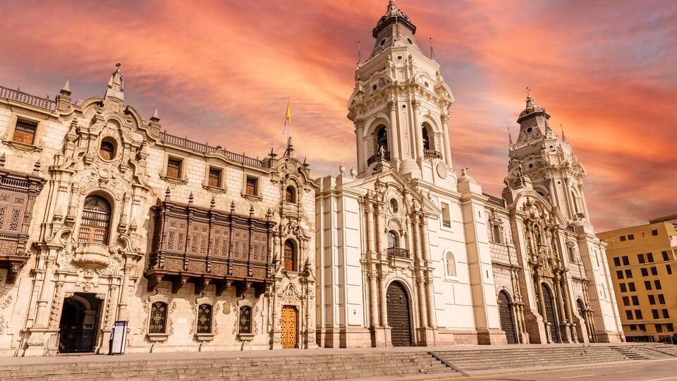 Uma catedral histórica com arquitetura ornamentada e uma torre de sino imponente.