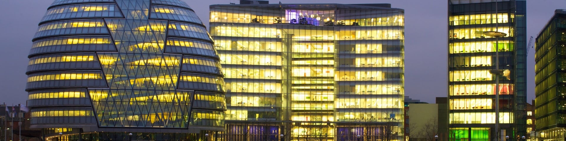 View of modern architecture along the River Thames at twilight in London, showcasing city life and vibrant illumination