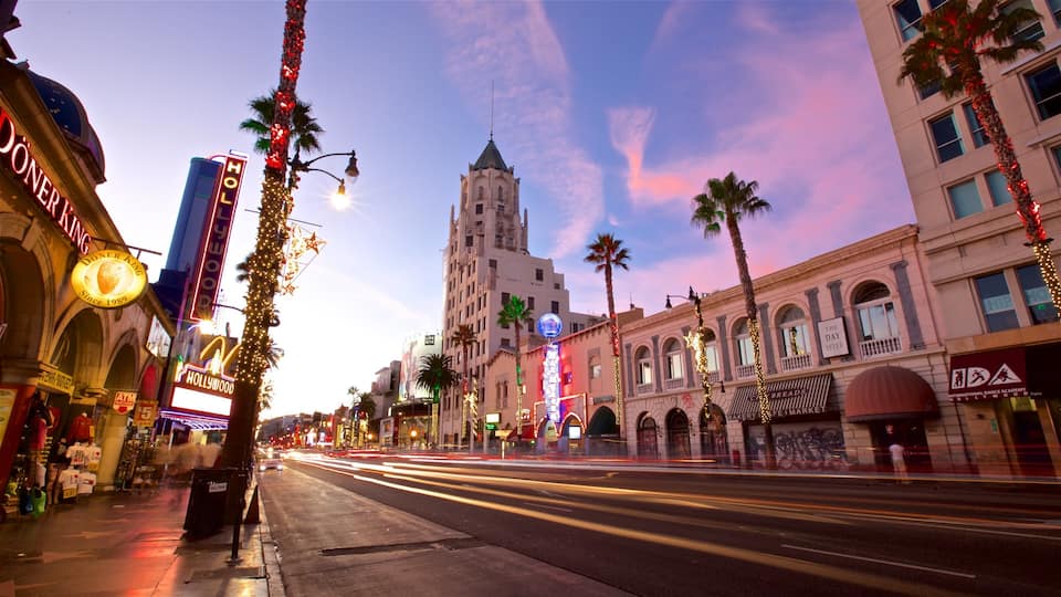 A street lined with palm trees, illuminated signs, and a prominent clock tower.