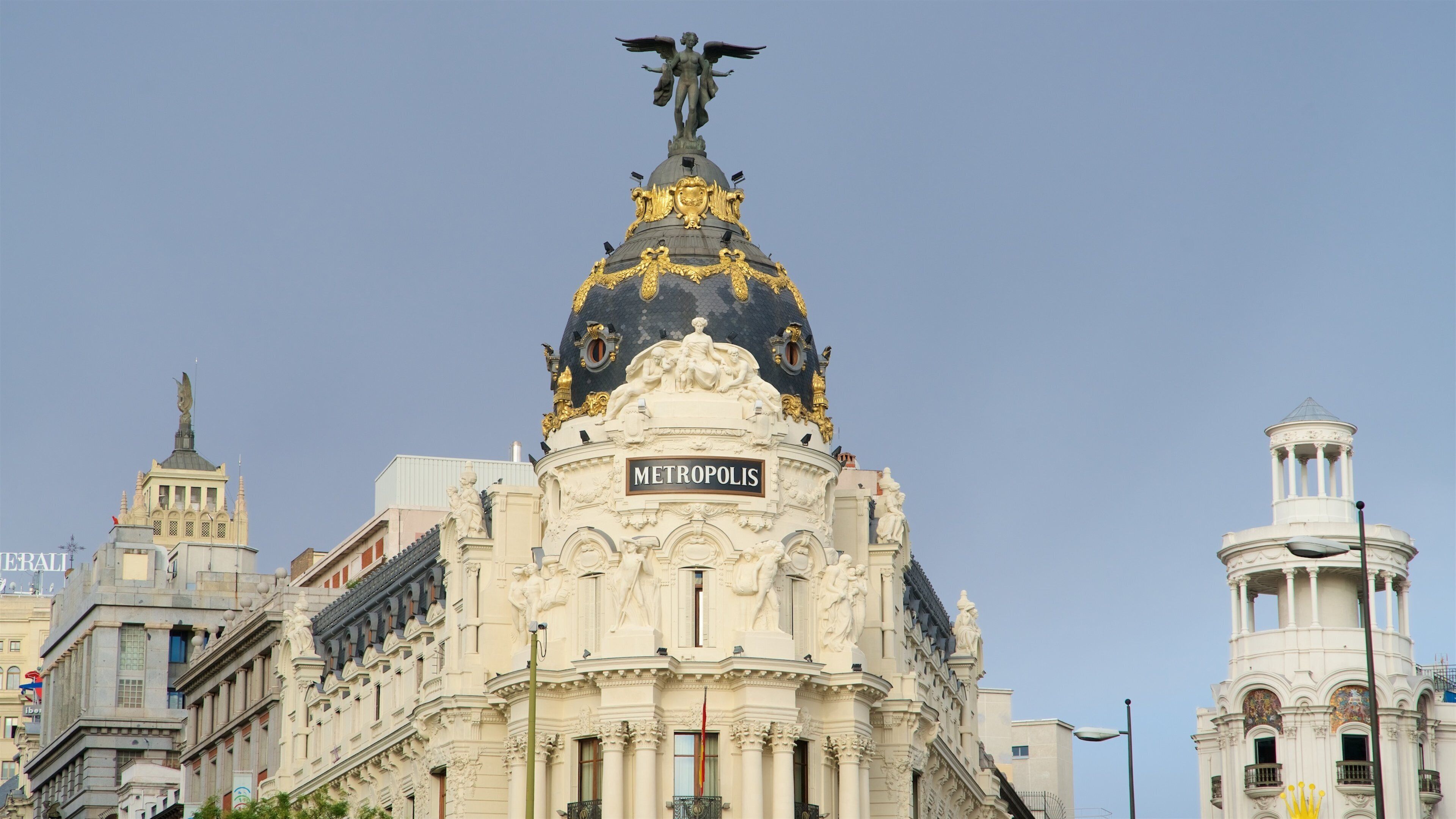 Un edificio imponente con una cúpula negra y dorada, esculturas ornamentadas y un letrero que dice “METROPOLIS”.