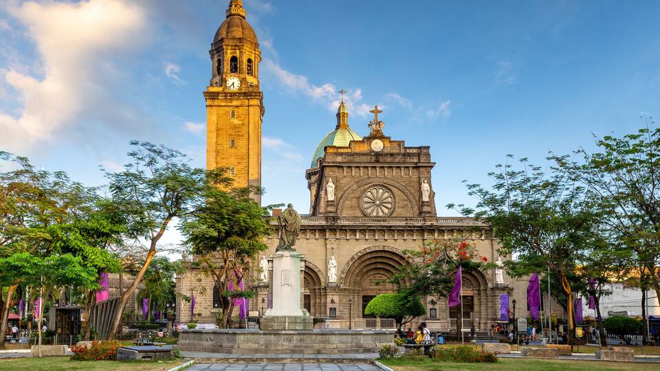 A historic church with a clock tower and a statue in front.