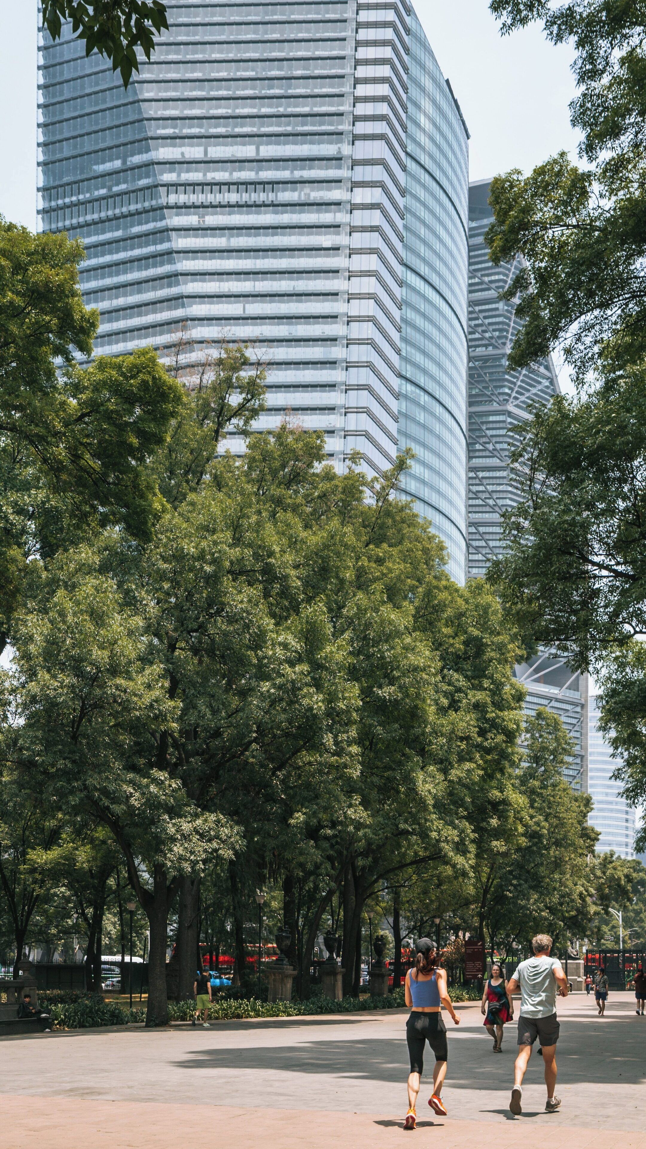 Visitors enjoy a sunny day in Chapultepec Park, surrounded by lush greenery and modern architecture in Miguel Hidalgo, Mexico City