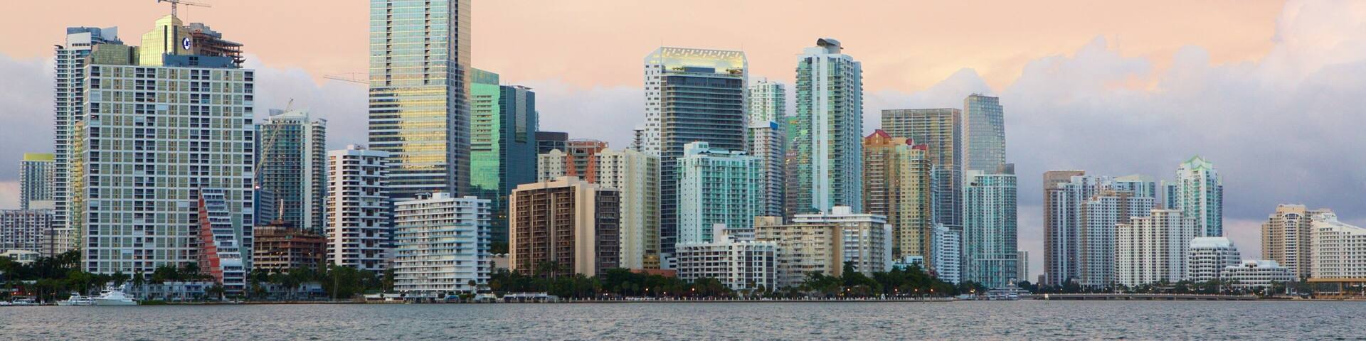 A city skyline with tall buildings and a body of water in the foreground.