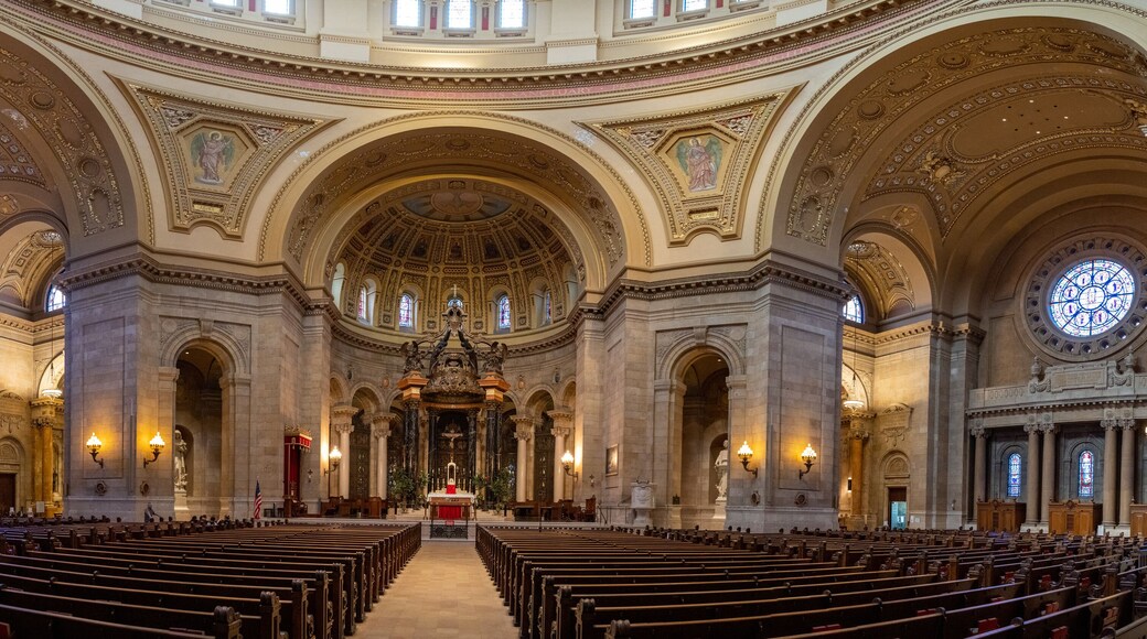 L’intérieur d’une église richement décorée, avec de hauts plafonds, des arcades travaillées et des vitraux.