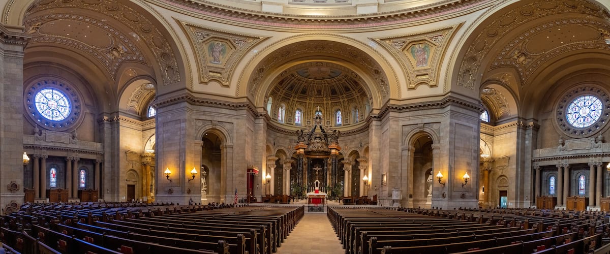 An ornate church interior with high ceilings, detailed arches, and stained glass windows.
