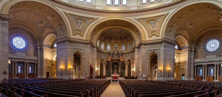 An ornate church interior with high ceilings, detailed arches, and stained glass windows.