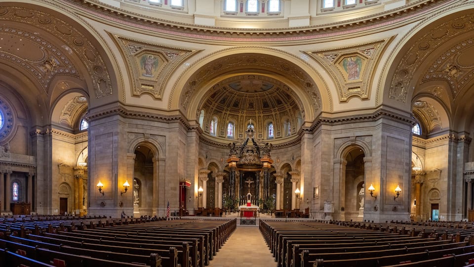 An ornate church interior with high ceilings, detailed arches, and stained glass windows.